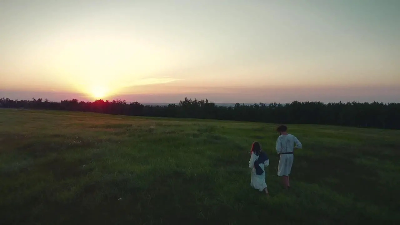 Two people walking through a field in a sunset