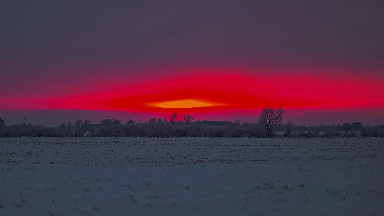 Bright red sunset as the sun dips behind the horizon and leaves a glowing crimson sky time lapse