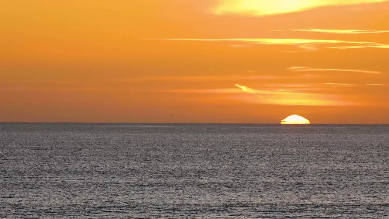 beautiful yellow sunset over a sea and some clouds in background at the beach with calm waves