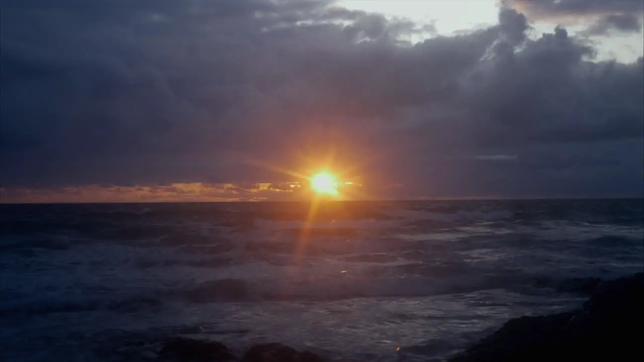 Seascape view with golden sunset rays of light shining through dark clouds STATIC SHOT