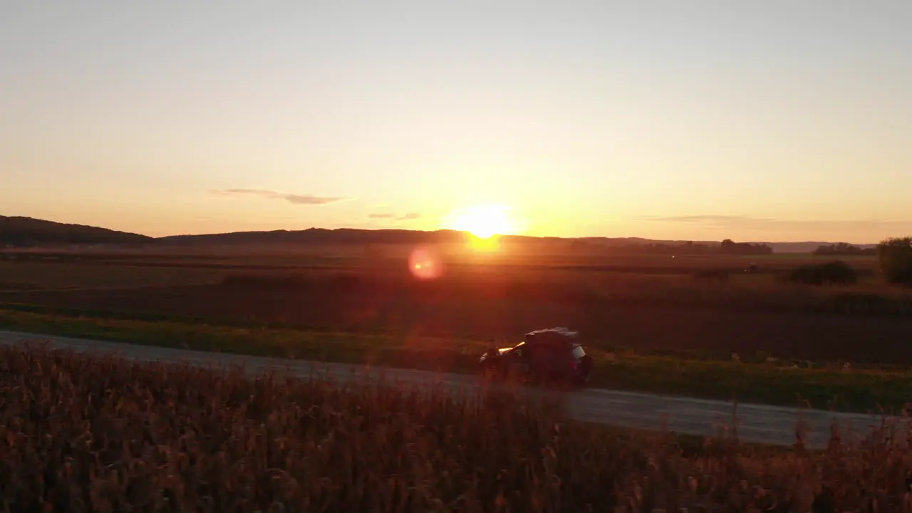 Road trip through countryside at sunset aerial arc shot