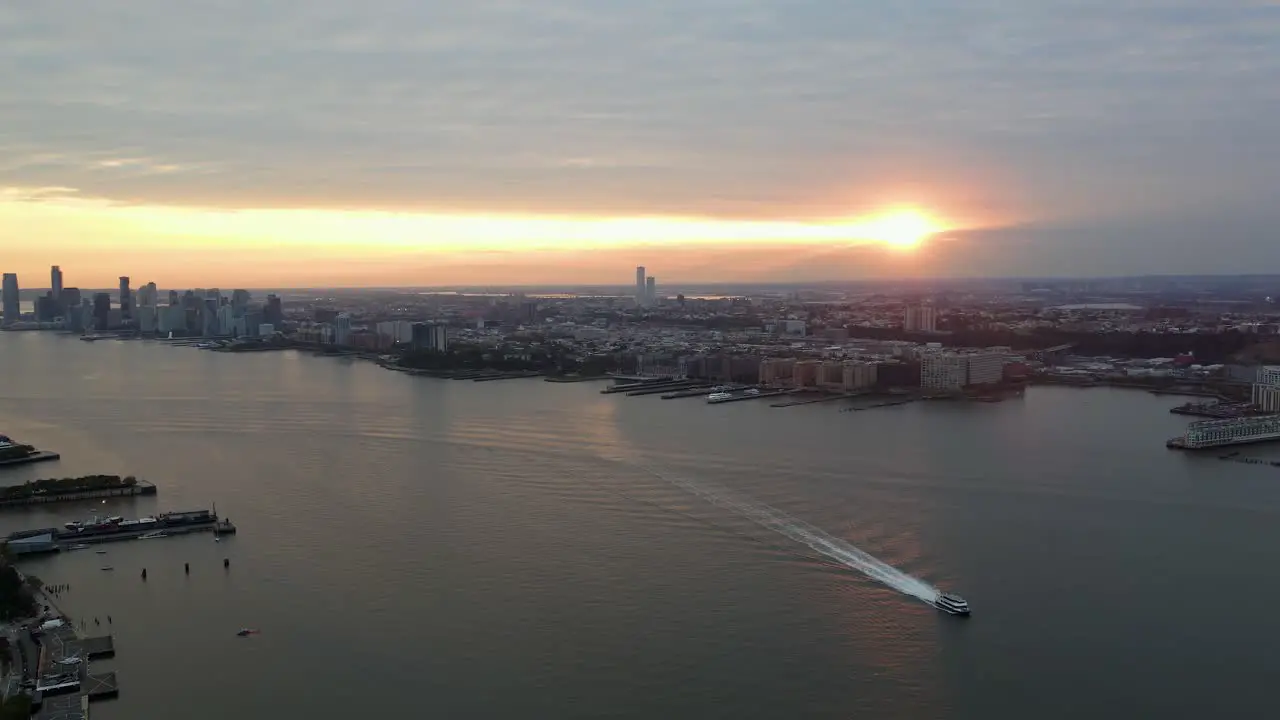 Aerial view of a boat with cloudy evening sky and the New Jersey city background pan drone shot