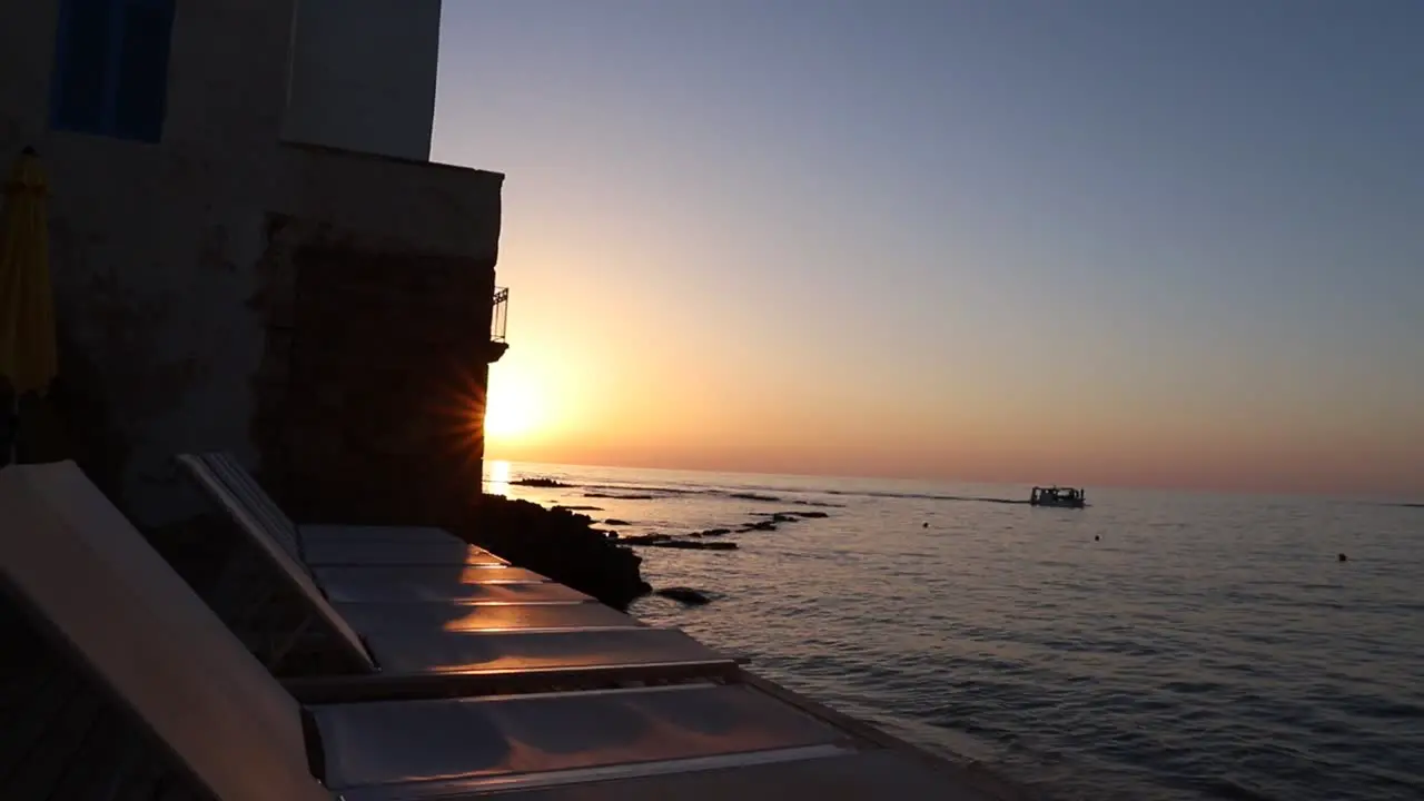 Picturesque beach view of calm ocean waters and boat at sunset Tyre Lebanon pan right reveal