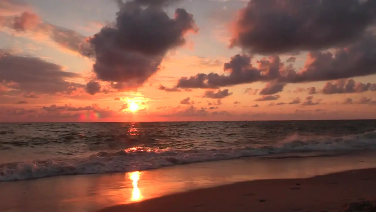 Dramatic beach sunrise burning the sky sun shining in red color during idyllic sea background