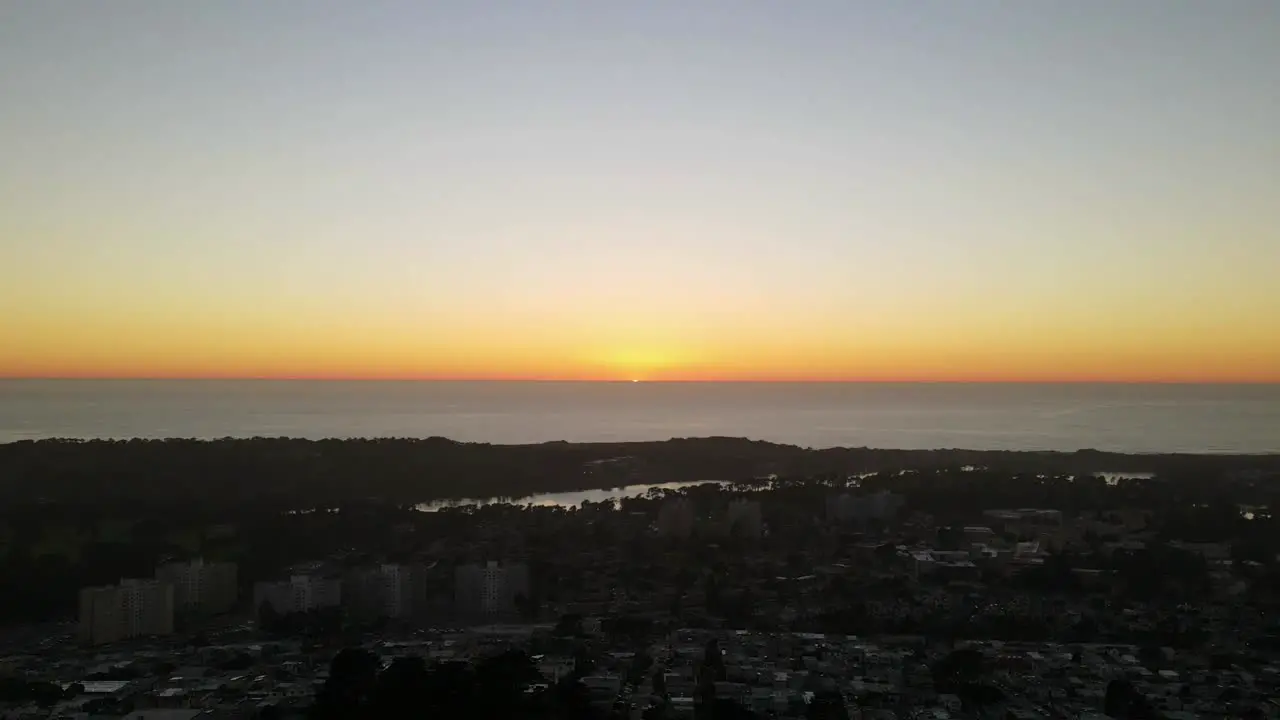 Sunset loop Over the Ocean and residential houses in foreground drone across the horizon