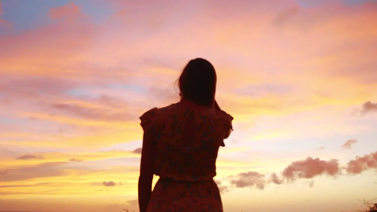 Beautiful young girl in a yellow dress looking at the sunset