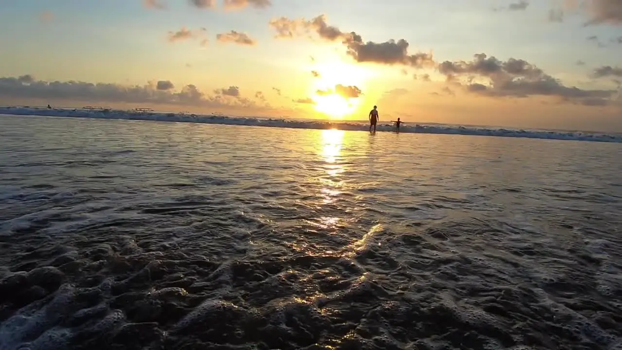 Waves flowing ashore on the beach in a sunset at Bali Indonesia while the sun is setting golden beautiful