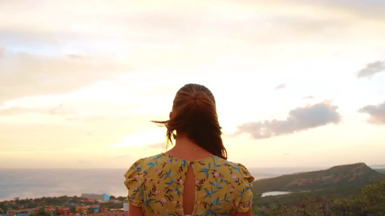 Pedestal of an attractive woman in a yellow dress looking to the sunrise