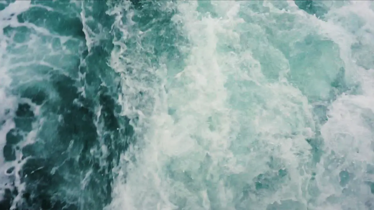 Slow motion froth splashing up behind boat creating blue and white imagery