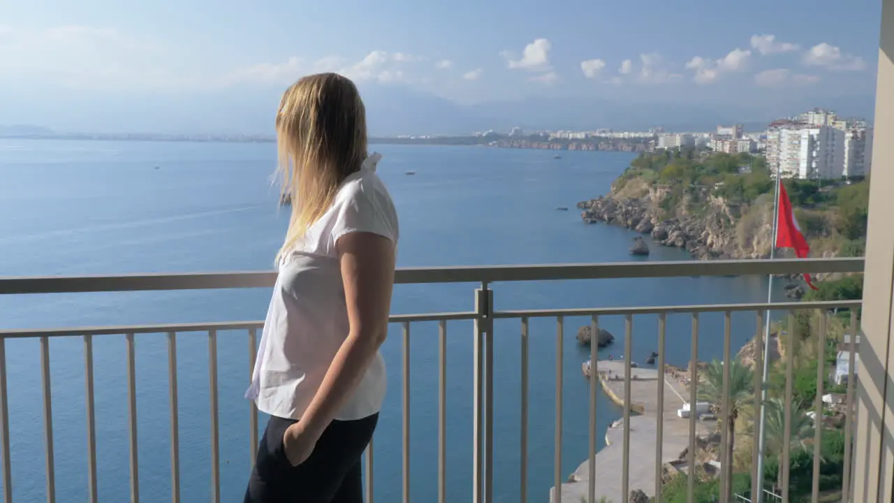 A woman talking to the phone on a hotel balcony against the beautiful scenery