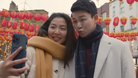 Young Asian Couple On Holiday Posing For Selfie On Mobile Phone In Chinatown London UK 2