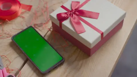 Close Up Shot Of Man Gift Wrapping Romantic Valentines Present In Box Next To Green Screen Mobile Phone