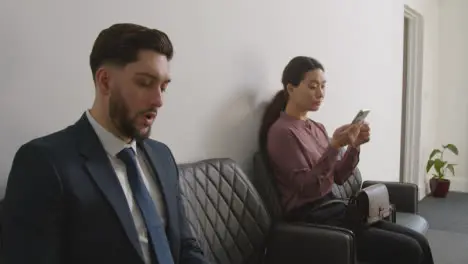 Female Candidate Wearing Suit In Office Waiting For Job Interview Looking At Mobile Phone 1