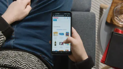 Overhead Shot Of Person At Home Shopping Online Looking At Costco Website On Mobile Phone 1