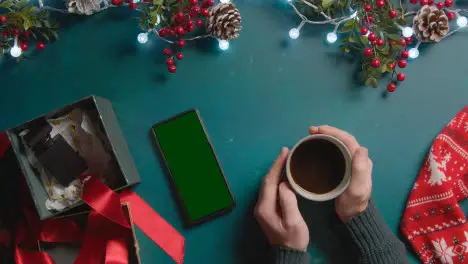 Overhead Shot Of Person With Green Screen Mobile Phone With Christmas Decorations And Gifts