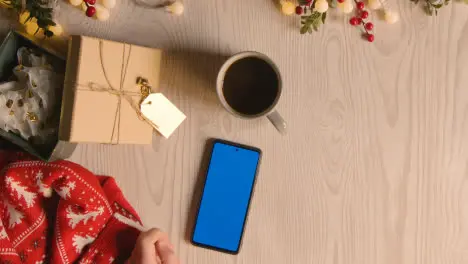 Overhead Shot Of Person Holding Blue Screen Mobile Phone With Christmas Decorations And Wrapping 5