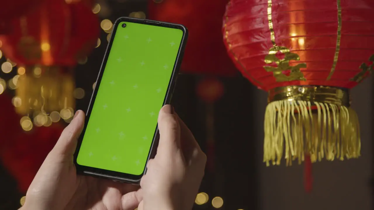 Hand Holding Green Screen Mobile Phone With Chinese Lanterns Hung In Background 3