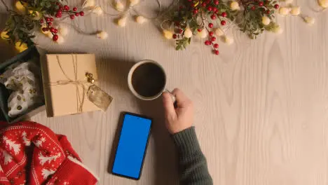 Overhead Shot Of Person Holding Blue Screen Mobile Phone With Christmas Decorations And Wrapping 4