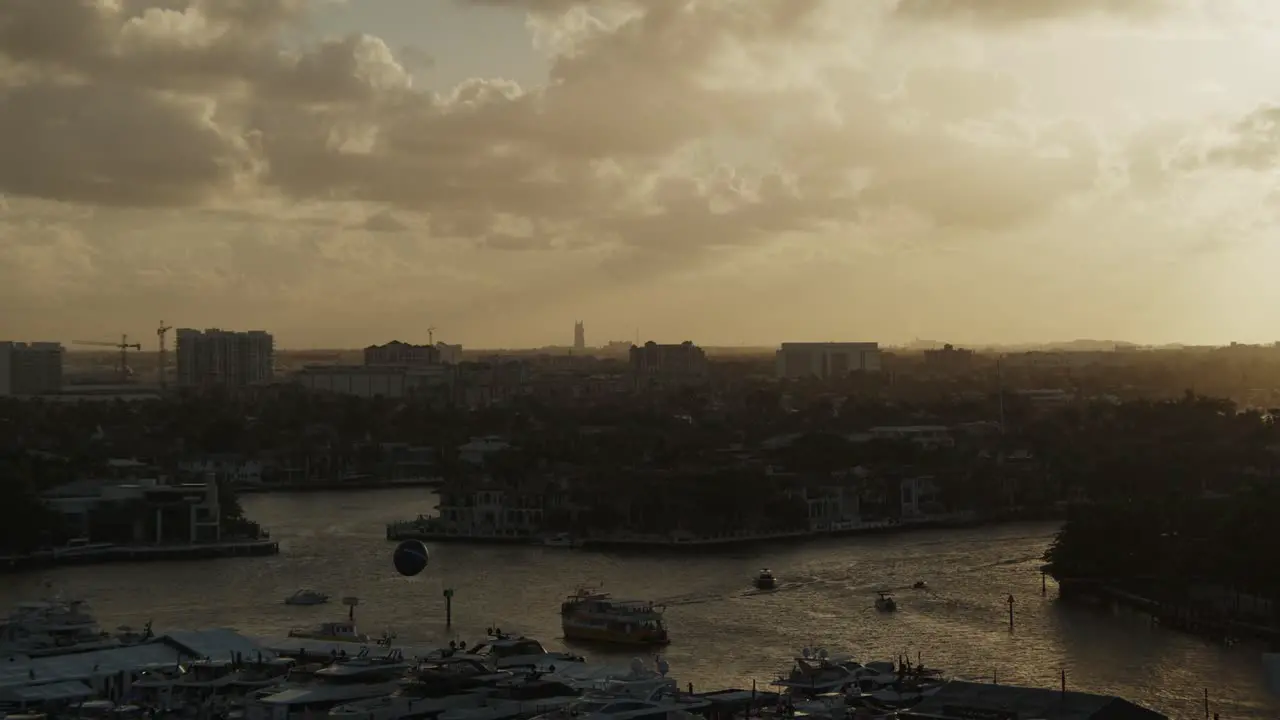 sunset over a coastal city in florida boats on the water in distance and sun shining through the clouds