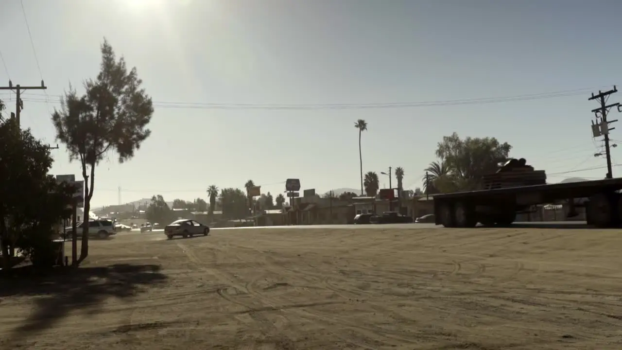 Slow motion of a large truck passes by on a dusty road through a small town in Baja California