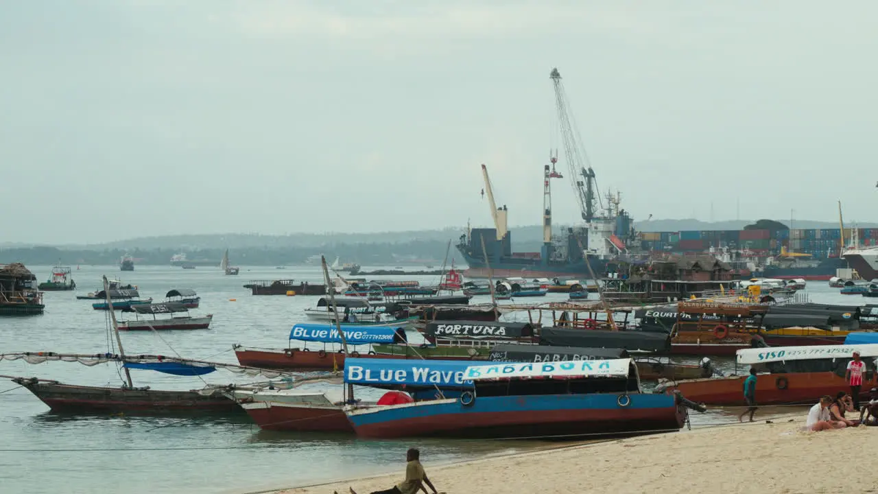 Boats anchored off the beach in Stone Town Zanzibar with the container port in the background