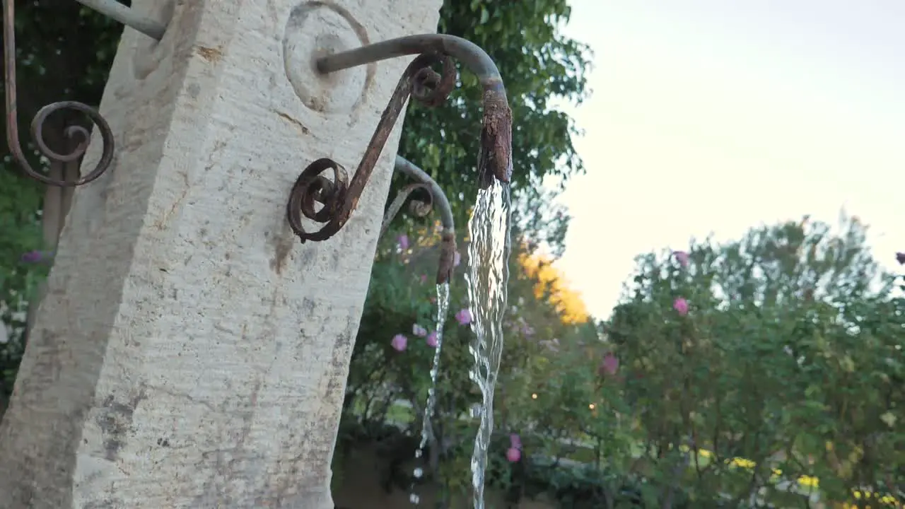 Slow motion footage of water flowing from a rusty spout on an outdoor fountain