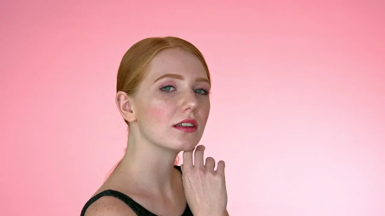 Beautiful redhead woman against pink background