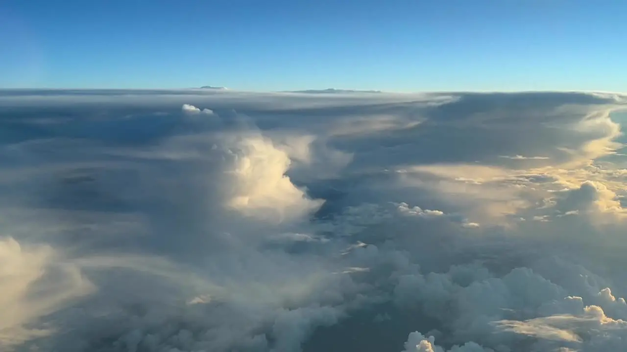 Aerial view from a jet cockpit near some huge cumulonimbus in the sunset during the cruise level