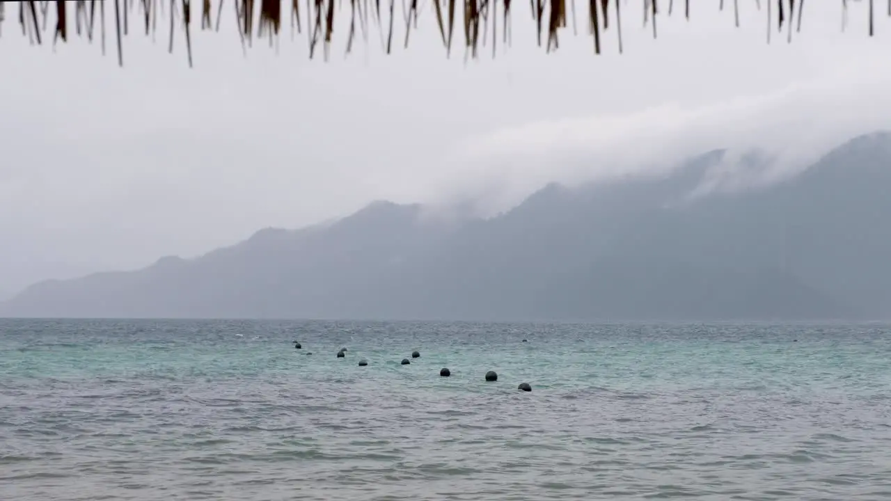 Ocean buoys bobbing in water on a wet grey cloudy and rainy day in remote tropical island destination