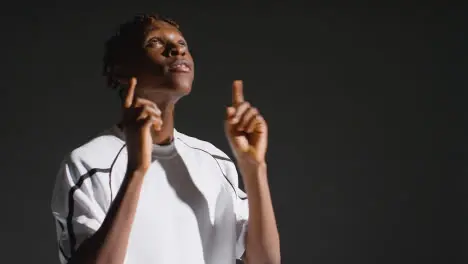 Low Key Studio Portrait Of Young Male Footballer Wearing Club Kit Celebrating Goal 3