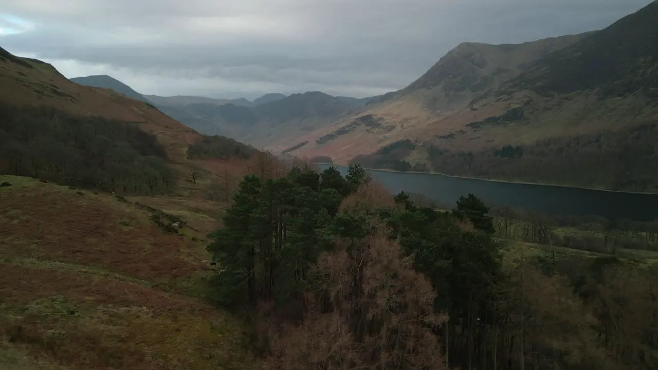 Lake filled valley reveal of Buttermere and distant mountains with stormy sky in English Lake District UK