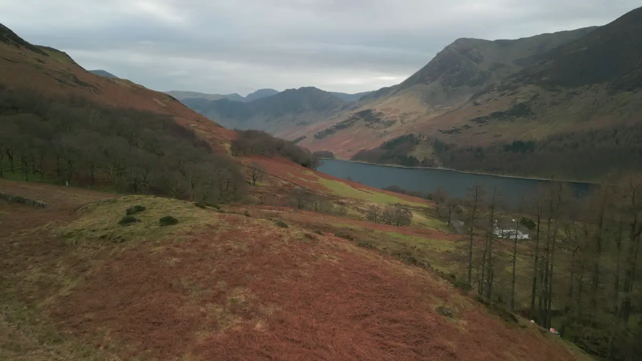 Flying towards dark lake surrounded by mountains in English Lake District UK