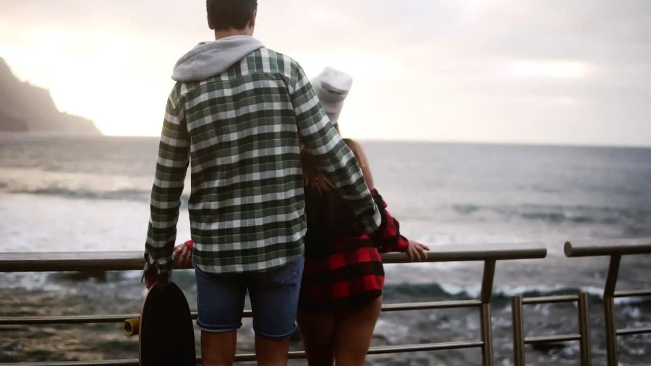 Woman Gazes At Ocean A Brunette Woman Shown From Behind Looks Out Over An Ocean In Front Of The Hills And Then Man Comes To Her To Embrace