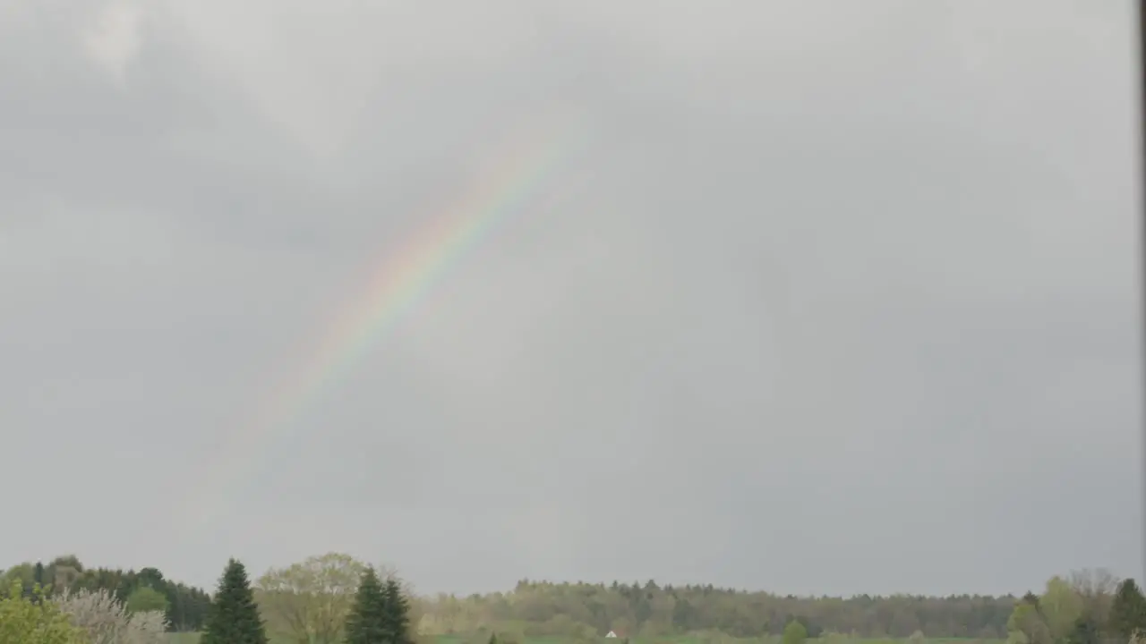 Rainbow appearing in sky over neighborhood after storm in afternoon Germany Europe