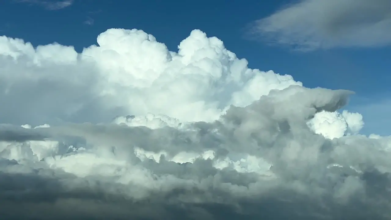 Aerial view taken from a jet cockpit of a huge white cumuloninmus during daylight