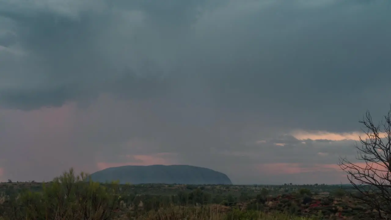 A time lapse of storm clouds rolling over Uluru in the Australian Outback during sunset