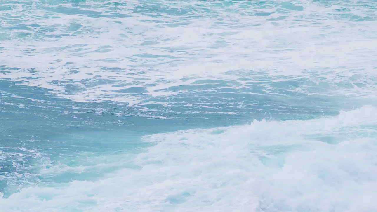 Big waves breaking near shorline creating foam and mist during strong winds