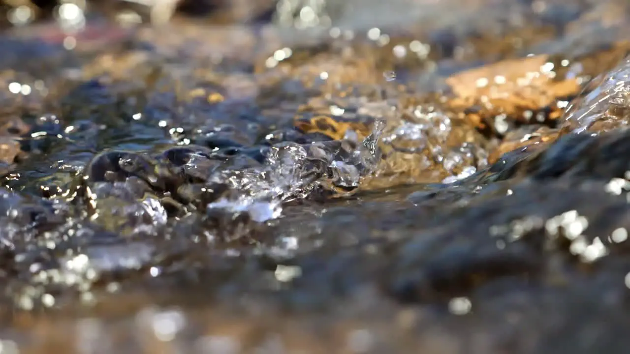 Slow motion tight shot of beautiful sparking water flowing down stream