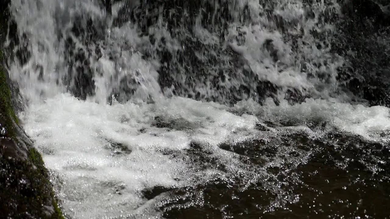 Bubbling whitewater hits base of waterfall shot in slow motion at 180 frames per second