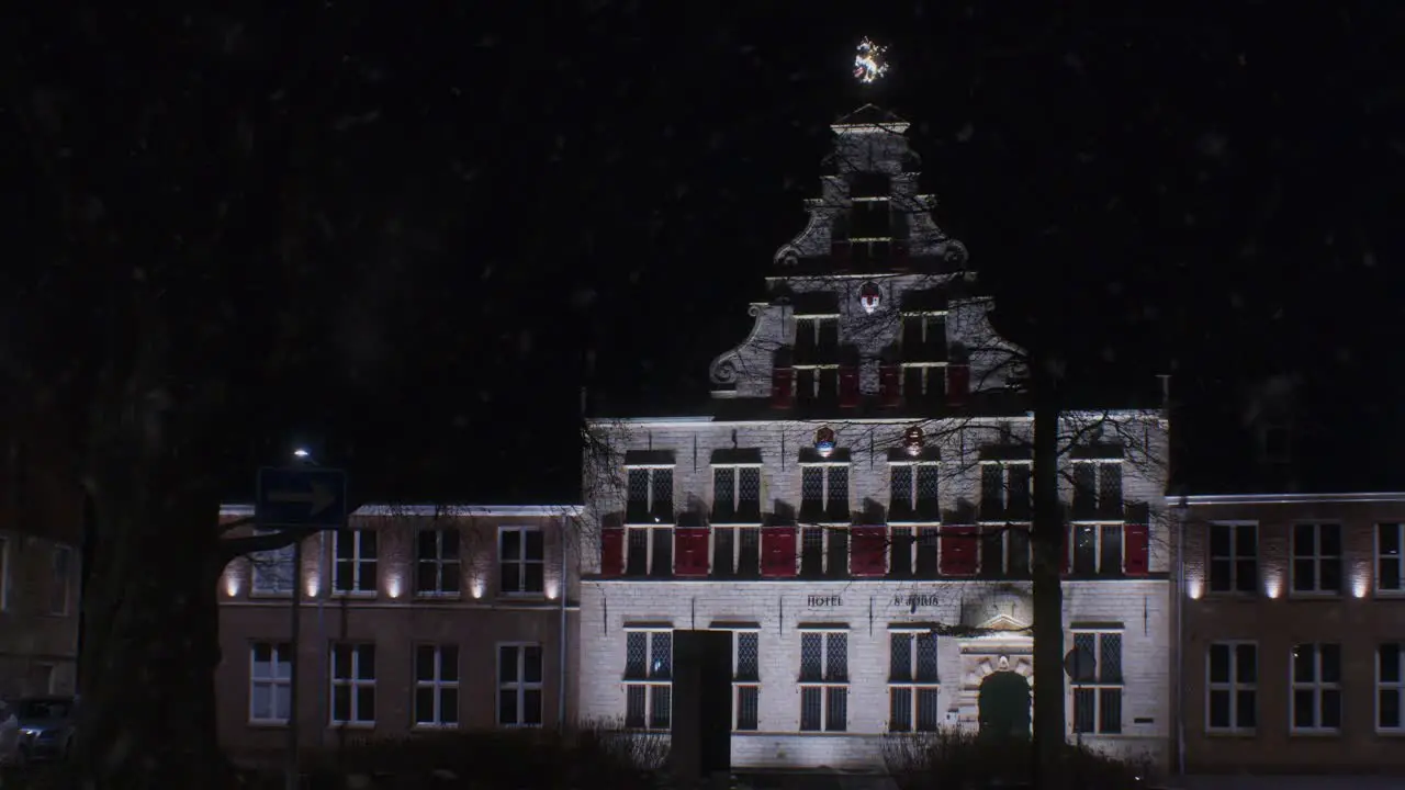 Winter snowfall in the night in Europe Netherlands Holland Dutch city town with lights and traditional architecture house building view