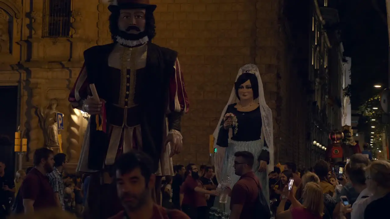 Large dancing decorative figures with men inside walking down the street in La Merce Festival