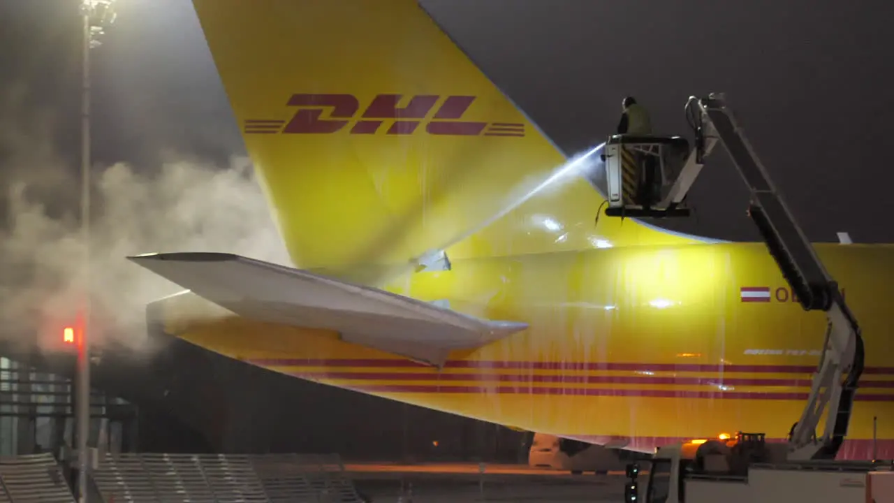 Tail and Elevator of DHL Freighter Airplane Getting De-icing Treatment during a Cold Winter Night