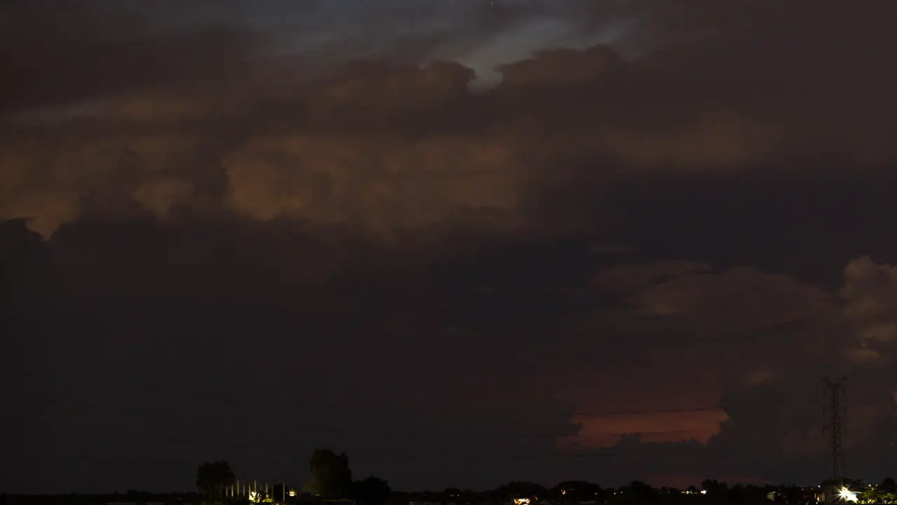 Flashing electric storm over pink red setting clouds over a setting sun horizon