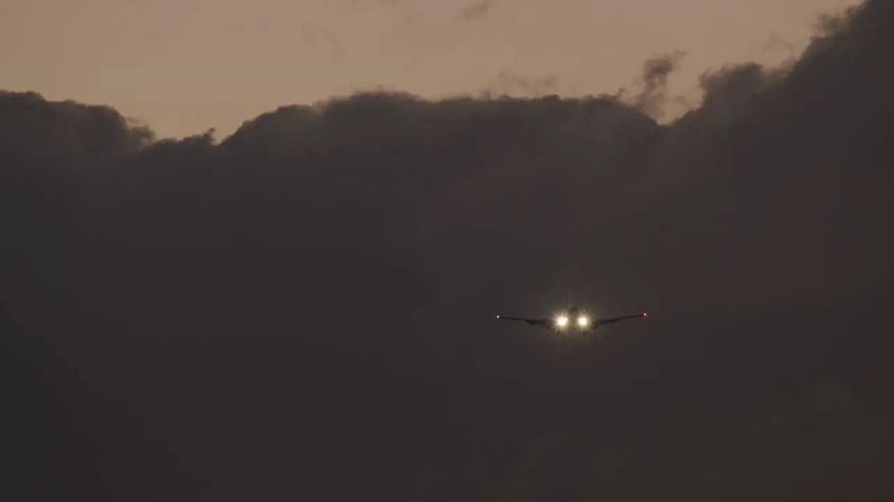 Plane with headlights ascending against heavy clouds in evening sky