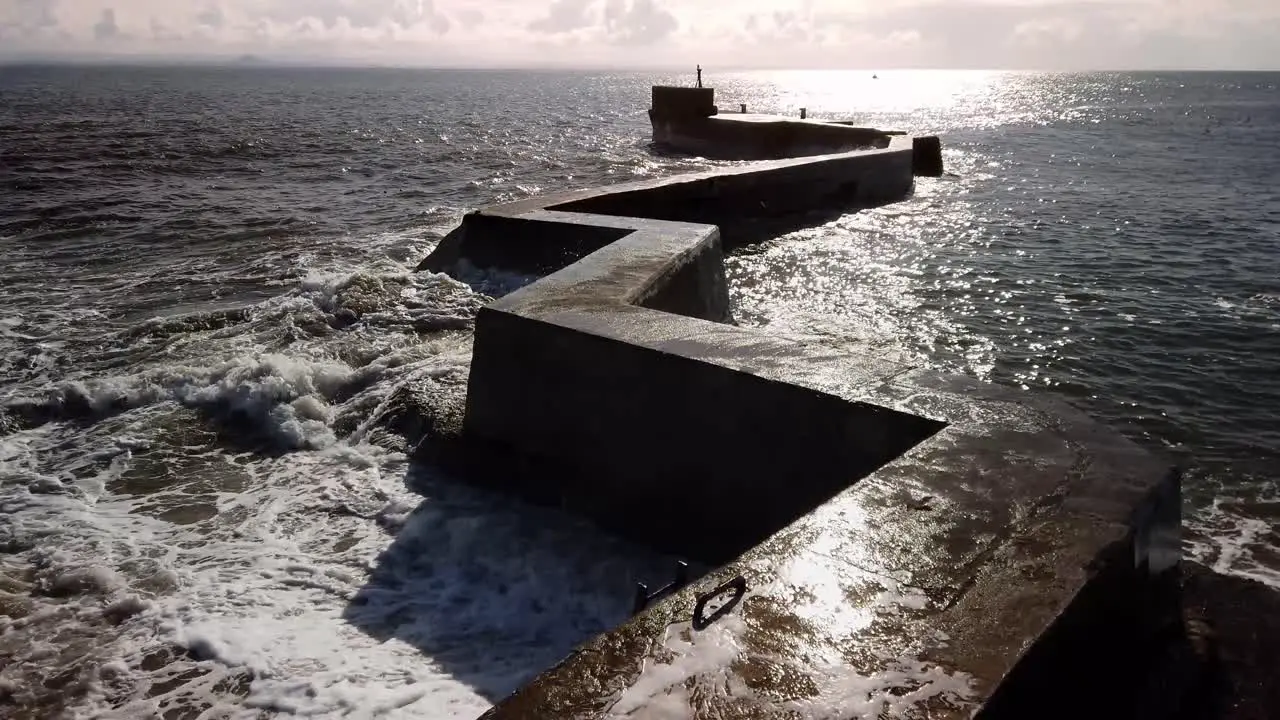 Popular photographic location of the zig-zag breakwater pier in St Monans Fife Scotland with storm waves breaking on a sunny day