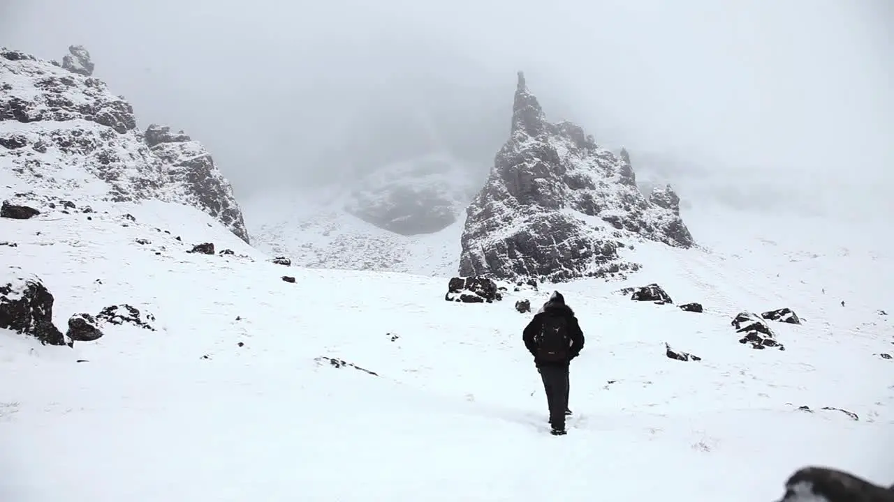 Adventurer couple walking through rocky mountains winter landscape snowy highlands Scotland static shot low angle