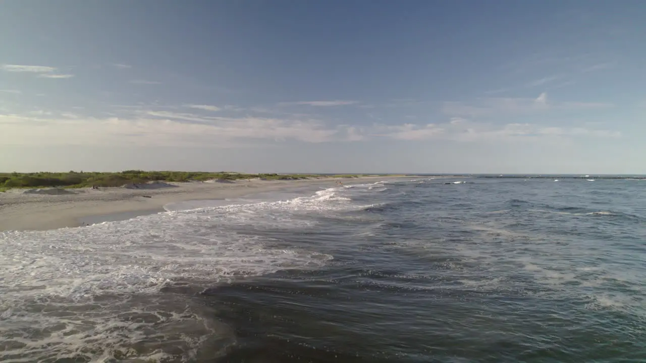 Aerial drone move down surf and beach on Long Beach Island with water splash near camera