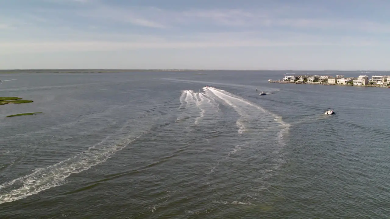 Boat speeding away from drone with two jetskis closely following on Long Beach Island