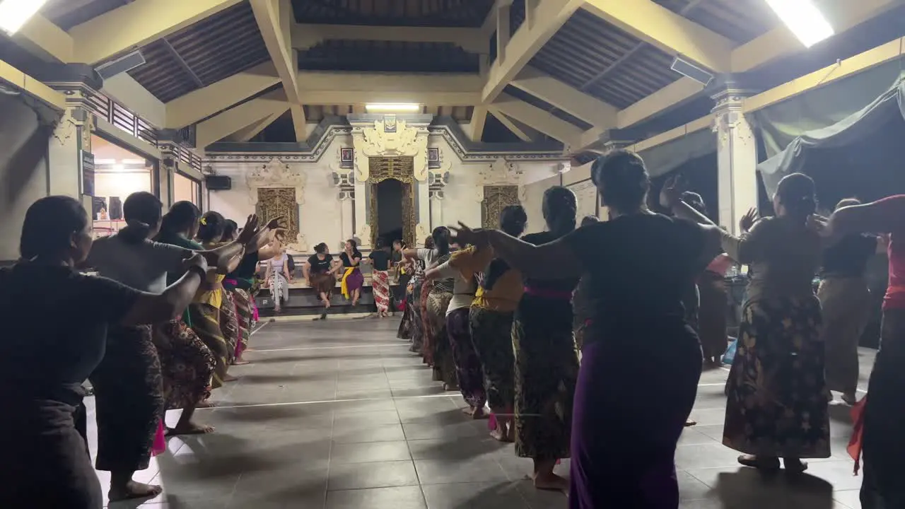 A large group of Balinese Women practicing together traditional Balinese dance in the temple at Night