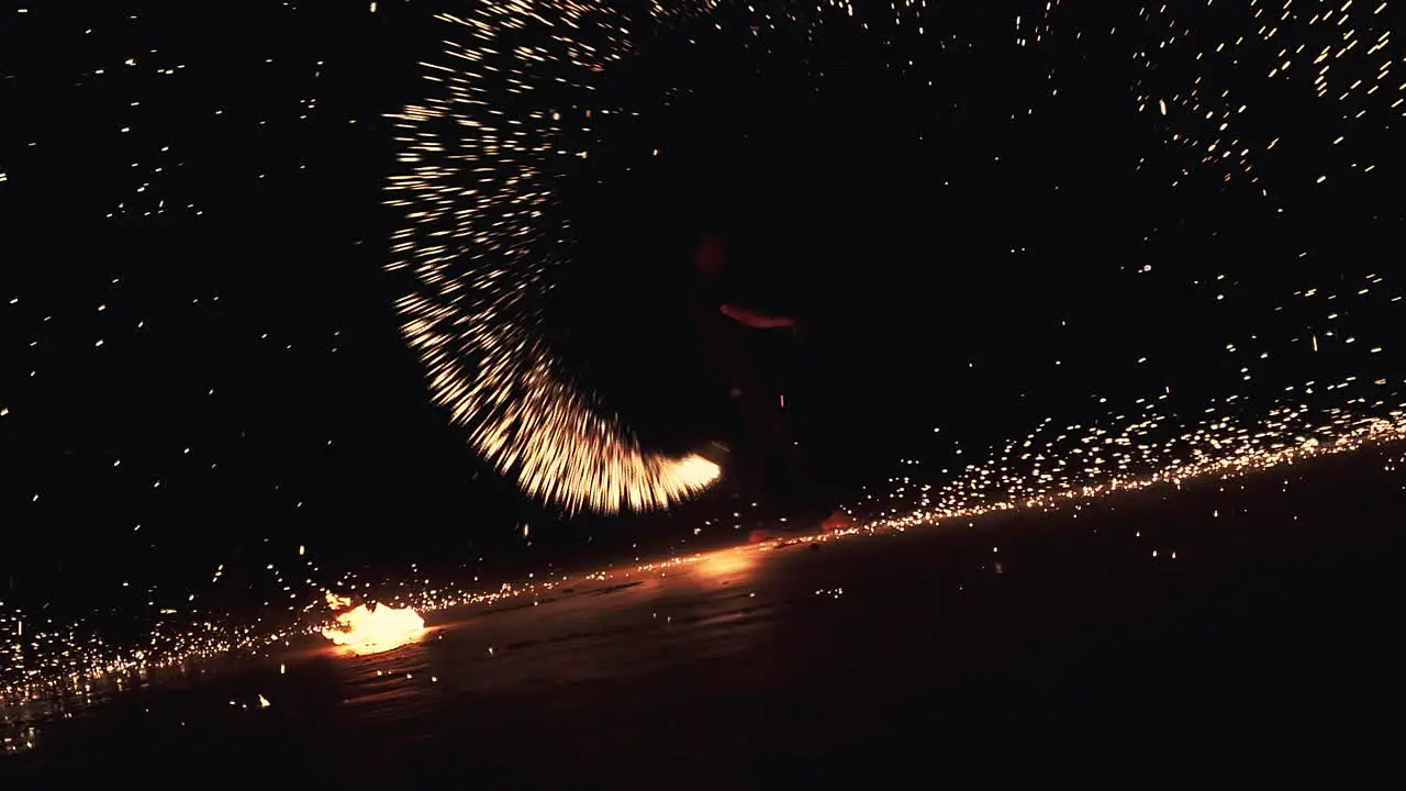 Performer spinning burning sparking torch on beach festival at night